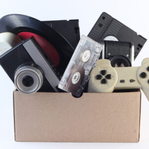 Caja de cartón con mandos de consolas, cámara de fotos y cintas